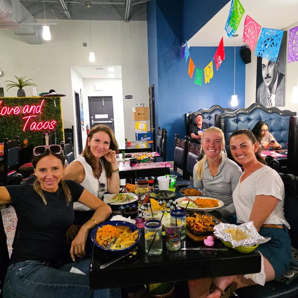 Four women smiling at a table filled with Mexican food and drinks at La Fiesta Mexican Cocina.